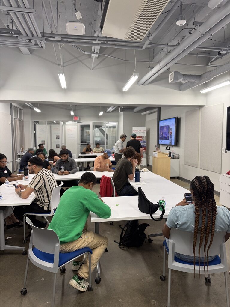 Attendees at long tables in the Pennovation classroom, heads down over laptops and phones.